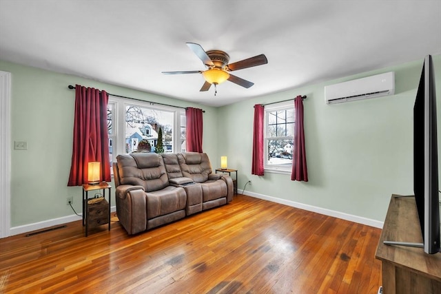 living room featuring hardwood / wood-style flooring, a wall unit AC, and ceiling fan