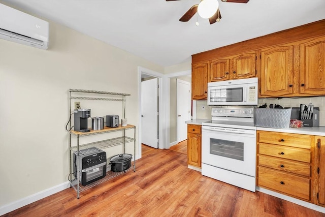 kitchen with tasteful backsplash, a wall unit AC, white appliances, and light wood-type flooring