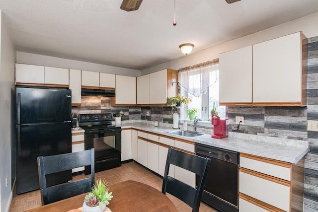 kitchen featuring a sink, light countertops, decorative backsplash, under cabinet range hood, and black appliances