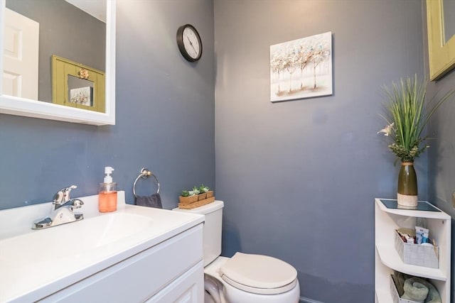 half bath with vanity, baseboards, and toilet