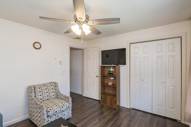 sitting room featuring dark wood-style flooring, a ceiling fan, visible vents, and baseboards