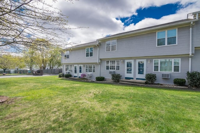 rear view of house with a lawn and an AC wall unit