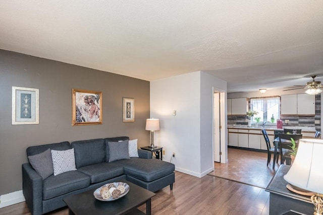 living room with baseboards, ceiling fan, and wood finished floors