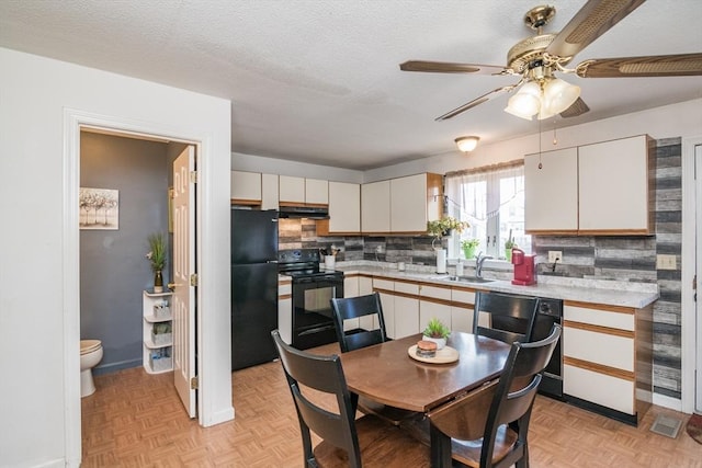 kitchen featuring a ceiling fan, a sink, light countertops, black appliances, and under cabinet range hood
