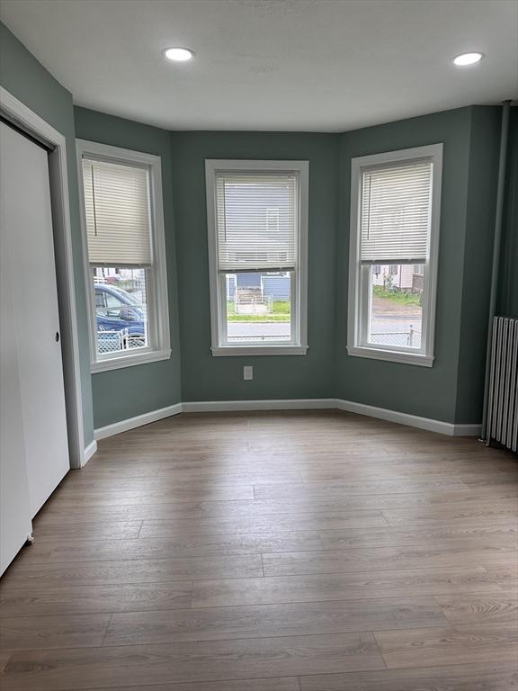 unfurnished room featuring radiator heating unit, baseboards, wood finished floors, and recessed lighting