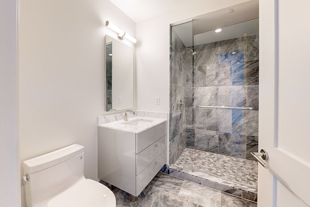 bathroom with toilet, vanity, and tiled shower