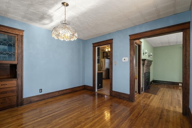 spare room featuring dark hardwood / wood-style floors, a fireplace, and an inviting chandelier