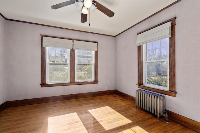 spare room with ornamental molding, a wealth of natural light, radiator, and light wood-type flooring