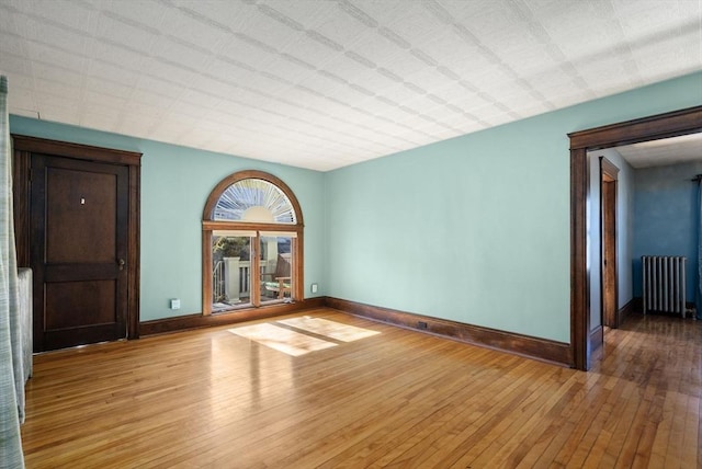 unfurnished room featuring radiator and light hardwood / wood-style floors