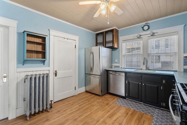 kitchen with radiator, crown molding, sink, appliances with stainless steel finishes, and light hardwood / wood-style floors