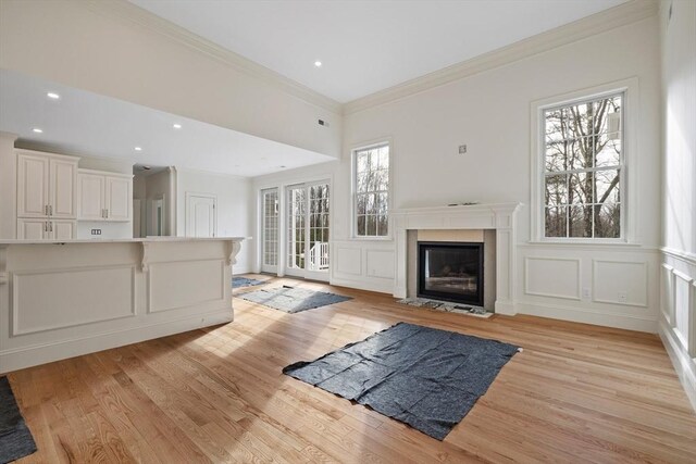 unfurnished living room with light wood finished floors, a fireplace with flush hearth, a decorative wall, and crown molding