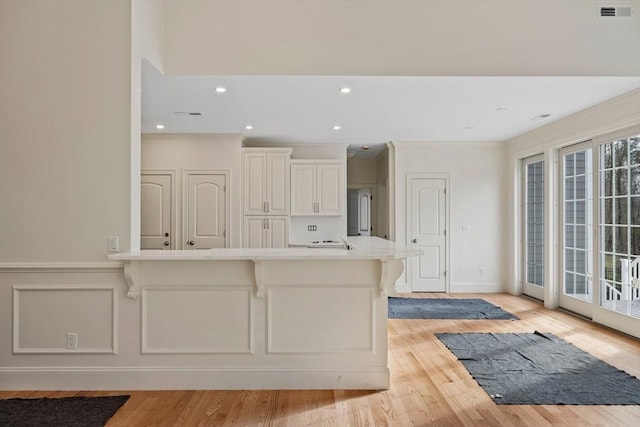 kitchen with visible vents, light countertops, crown molding, light wood-type flooring, and white cabinetry