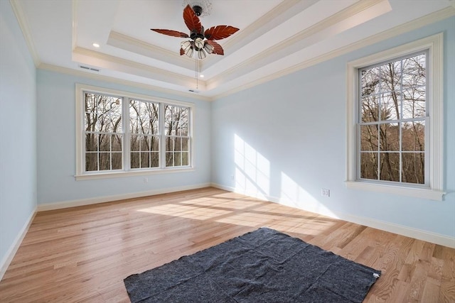 interior space with light wood-type flooring, a tray ceiling, a healthy amount of sunlight, and visible vents