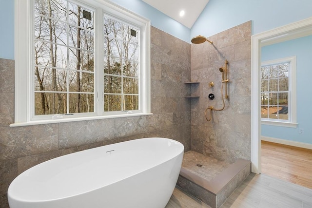 bathroom with baseboards, tiled shower, lofted ceiling, wood finished floors, and a freestanding tub