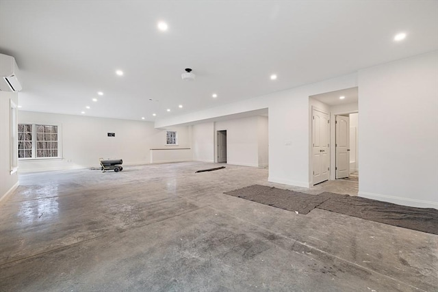 unfurnished living room with concrete flooring, recessed lighting, a wall mounted air conditioner, and baseboards