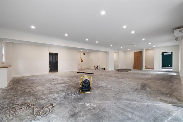 garage with a wall mounted AC, baseboards, and recessed lighting