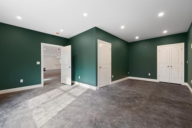 unfurnished bedroom featuring concrete floors, baseboards, a closet, and recessed lighting