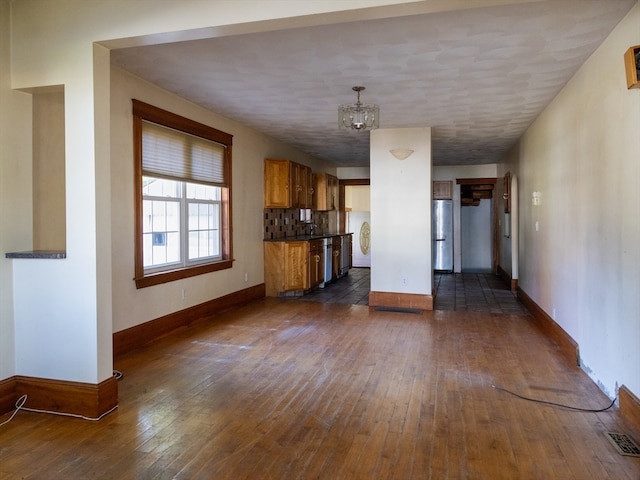 unfurnished living room featuring a notable chandelier and dark hardwood / wood-style floors