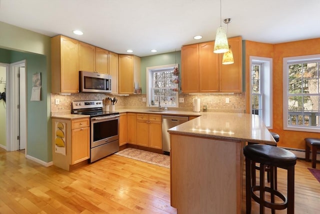 kitchen featuring appliances with stainless steel finishes, sink, hanging light fixtures, a kitchen breakfast bar, and kitchen peninsula