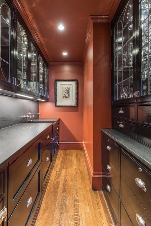 bar with ornamental molding and light wood-type flooring