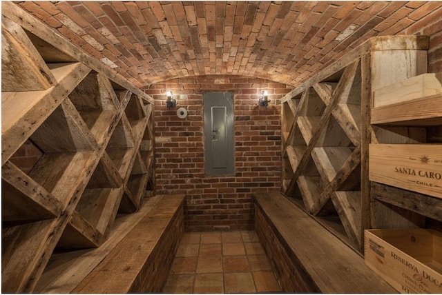 wine area featuring brick ceiling, brick wall, electric panel, and vaulted ceiling