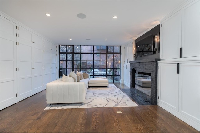 living room with expansive windows, wood-type flooring, and a brick fireplace