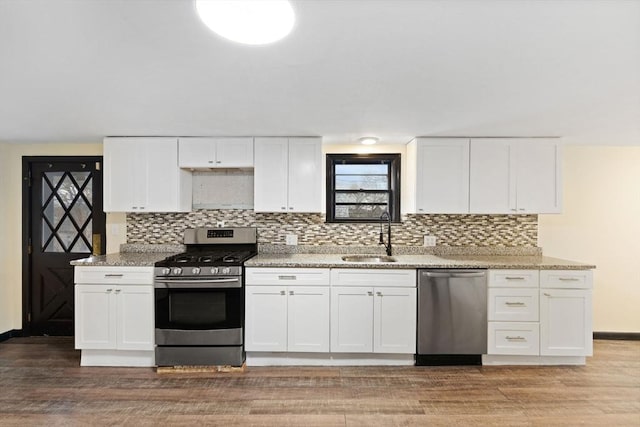 kitchen featuring light wood-type flooring, appliances with stainless steel finishes, white cabinets, and light stone countertops