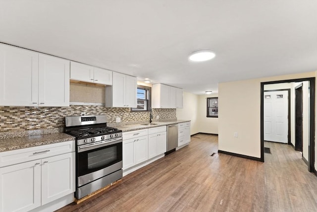 kitchen featuring light hardwood / wood-style flooring, light stone counters, stainless steel appliances, and white cabinetry