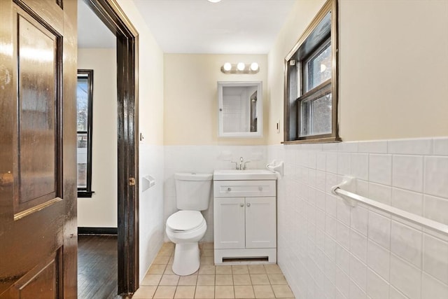 bathroom featuring toilet, tile patterned flooring, tile walls, and vanity