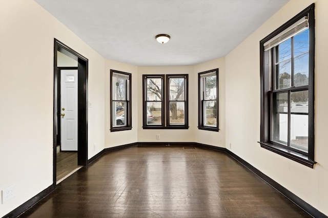 spare room with a healthy amount of sunlight and dark hardwood / wood-style floors