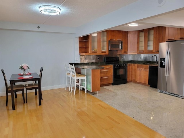 200 Cove Way Unit 607, Quincy, MA 02169 - kitchen featuring black appliances, brown cabinets, glass insert cabinets, and a kitchen breakfast bar