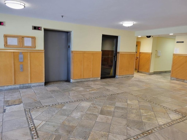 200 Cove Way Unit 607, Quincy, MA 02169 - empty room featuring elevator, a wainscoted wall, stone tile flooring, a pendent fire sprinkler, and wooden walls