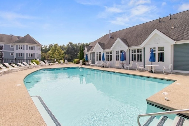 pool with a patio area and fence