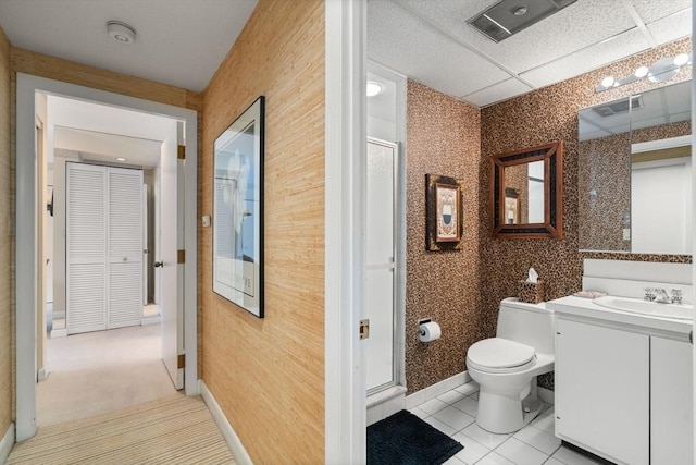 bathroom featuring toilet, vanity, walk in shower, tile patterned floors, and a paneled ceiling