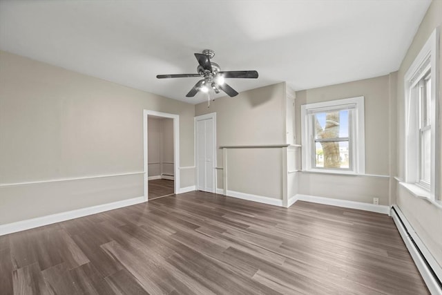 interior space featuring baseboards, a ceiling fan, a baseboard heating unit, and wood finished floors