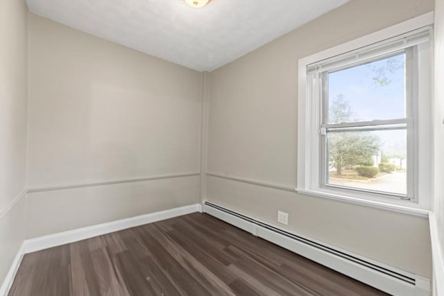 spare room with baseboards, dark wood finished floors, and a baseboard heating unit