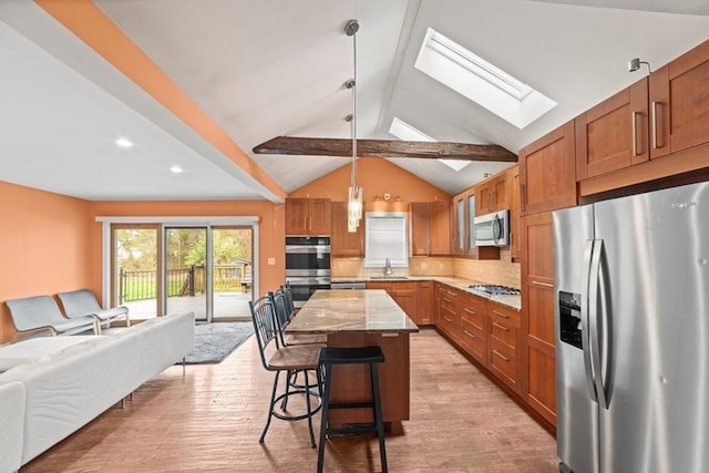 kitchen with a kitchen island, open floor plan, light wood-type flooring, a sink, and appliances with stainless steel finishes
