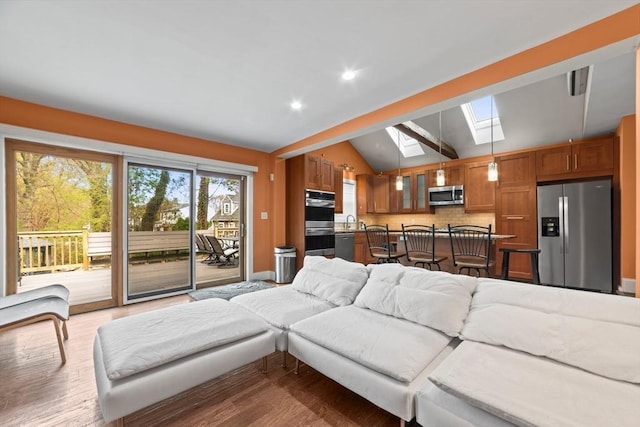 living room with recessed lighting, baseboards, wood finished floors, and lofted ceiling with skylight