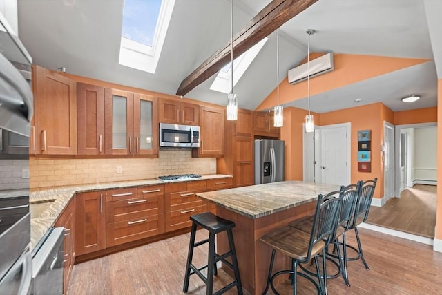 kitchen with appliances with stainless steel finishes, a breakfast bar area, brown cabinets, and light wood-style flooring
