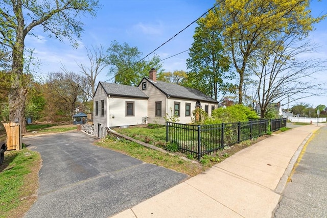 bungalow-style house featuring a fenced front yard and a chimney