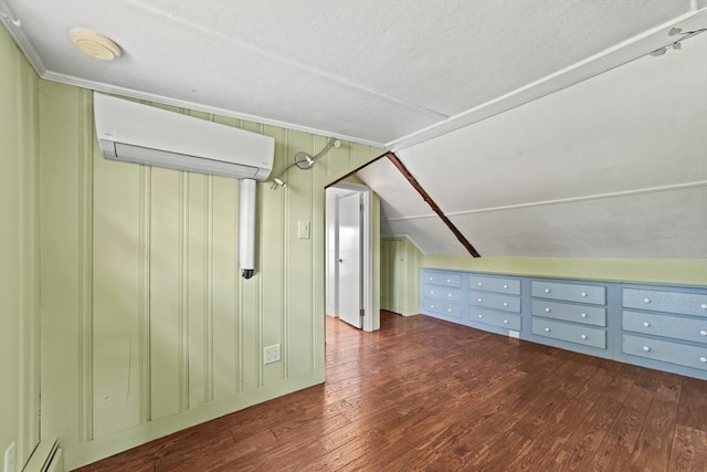 additional living space with wood finished floors, a baseboard heating unit, a wall unit AC, and vaulted ceiling