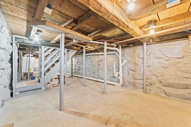 unfinished basement with water heater and stairs