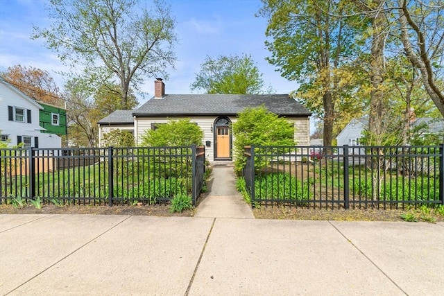 bungalow-style home with a chimney, a fenced front yard, and a front yard