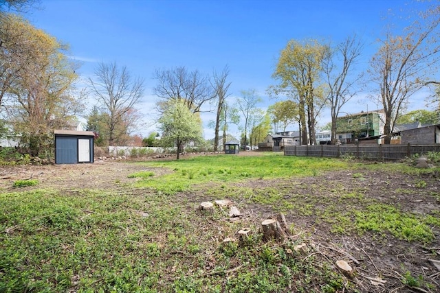 view of yard featuring fence, a storage unit, and an outdoor structure