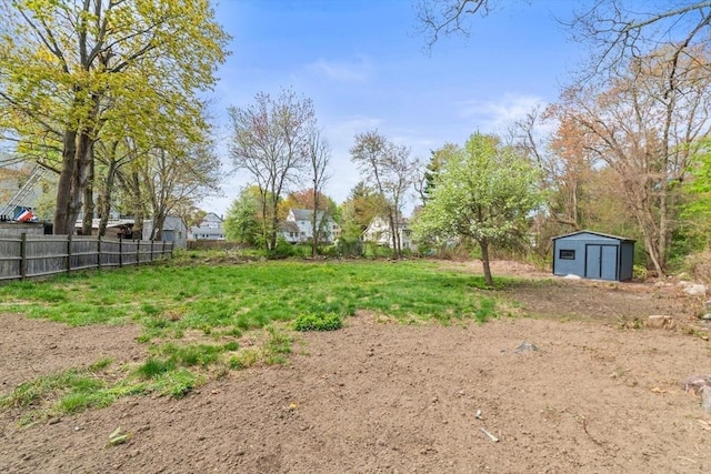 view of yard with a storage shed, fence, and an outbuilding