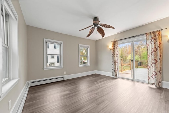 empty room featuring plenty of natural light, a baseboard radiator, ceiling fan, and wood finished floors