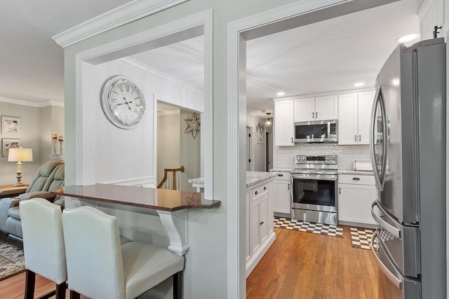 14 Mossman Rd, Westminster, MA 01473 - kitchen with appliances with stainless steel finishes, backsplash, white cabinetry, light wood-style floors, and a breakfast bar
