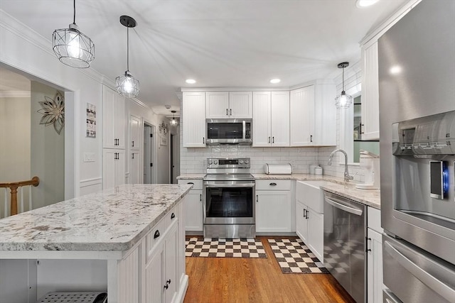 14 Mossman Rd, Westminster, MA 01473 - kitchen with stainless steel appliances, ornamental molding, light floors, a sink, and white cabinets