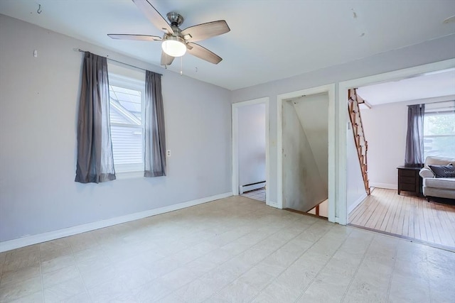 empty room featuring a baseboard radiator, a ceiling fan, and baseboards