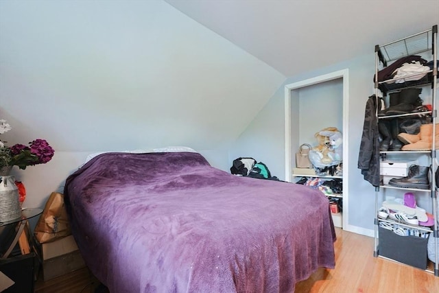 bedroom with wood finished floors and vaulted ceiling
